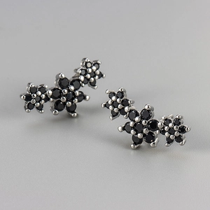Macro view of black zircon micro-pave flower stud earrings in silver settings