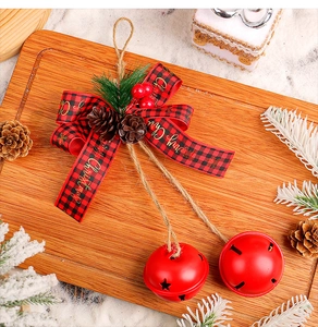 Detail of Christmas bell ornament with pine cones, red berries and plaid bow on wood