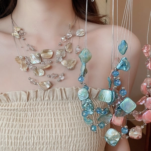 Close-up of layered necklace with irregular shell beads and crystals on a model
