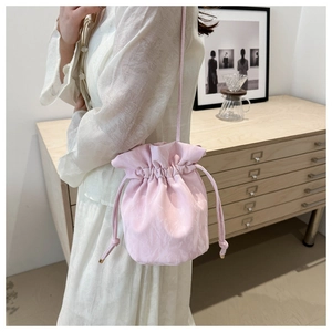 Macro shot of light pink satin drawstring bucket bag with minimalist cord strap and metal buckles