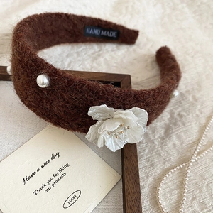 Macro shot of brown velvet headband with white pearl accents and handmade label