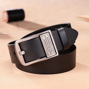 Détail de la ceinture en cuir noir pour homme avec boucle argentée et passant métallique gravé