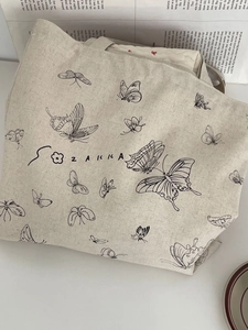 Macro detail of beige canvas tote bag with butterfly prints and vintage floral lining