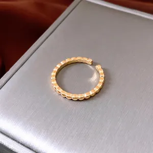 Gold plated open ring with textured beaded edges on a grey luxury display surface
