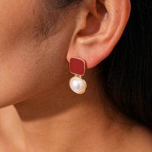 Gros plan d'une boucle d'oreille géométrique en émail rouge et perle sur le mannequin