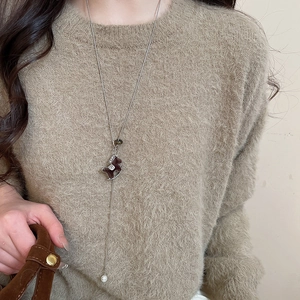 Détail du collier avec pendentif cheval à bascule en velours marron et perle élégante