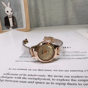 Elegant rose gold small dial watch for women with mesh strap on vintage paper background