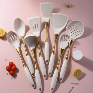 8-piece white silicone and gold stainless steel cooking utensils set on pink background