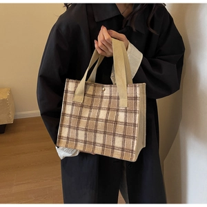 Close-up of brown and beige checkered canvas tote bag with woven handles and snap closure