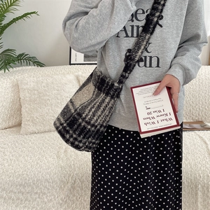 Detail of plush black and white checkered bucket bag worn with a gray hoodie