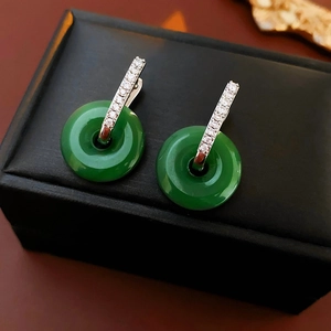 Détail de boucles d'oreilles en jade vert rond avec incrustation argent et diamants