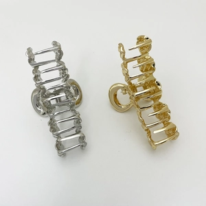 Detail of gold and silver wavy alloy hair claws with hollow design on white background