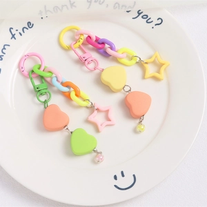 Close-up of colorful heart and star charms with plastic chain on a white plate