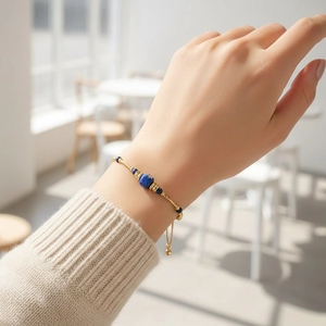 Detail of adjustable gold chain bracelet with blue sodalite beads on a model wrist