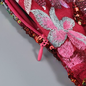 Close-up of burgundy sequin embroidery and invisible zipper detail on the dress