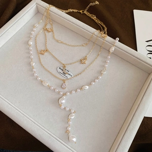 Detail of multi-layer gold necklace featuring star charms and teardrop zircon accents