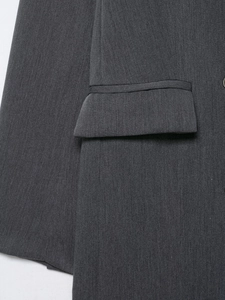 Gros plan d'un blazer gris foncé montrant la texture sergé et le détail de la poche