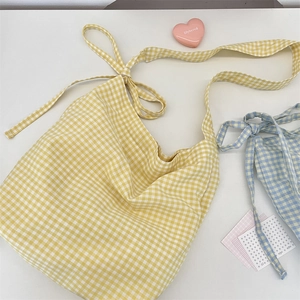 Detail of blue and yellow gingham canvas tote bags with adjustable ribbon tie shoulder straps