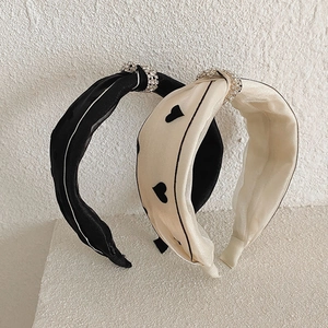 Elegant knotted headbands in black and beige with rhinestone rings and heart patterns