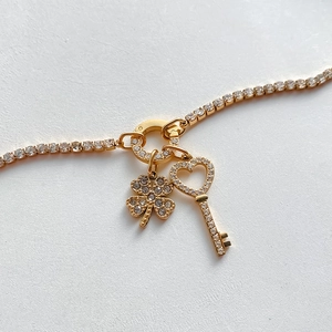 Dettaglio del braccialetto placcato oro 14K con ciondoli a trifoglio e chiave a cuore