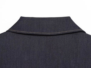 Détail du col d'une veste en jean bleu marine avec surpiqûres jaunes et texture sergé