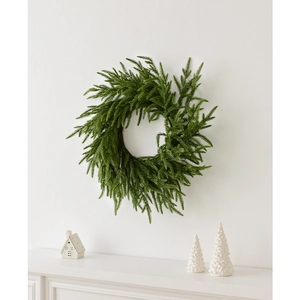 Realistic Norfolk pine Christmas wreath with dense green foliage hanging on a white wall