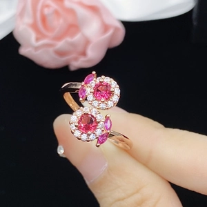 Rose gold floral open ring with red rubies and diamonds on a black background