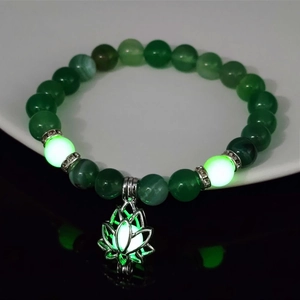 Macro shot of luminous lotus flower charm and green glow beads on a yoga bracelet