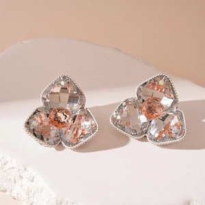Macro shot of silver flower earrings with clear crystals and amber centers on stone