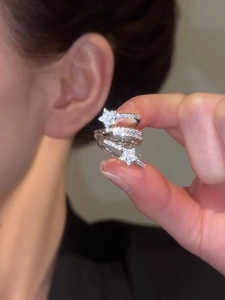 Close-up of silver zircon star multi-layer ear cuff held by hand to show detail