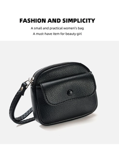 Close-up of black pebbled leather mini wallet featuring silver metal zipper and hand strap