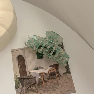 Detail of large marble green acetic hair claw clip on vintage postcard background