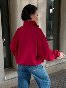 Outdoor-Aufnahme eines leuchtend roten Oversize-Sweatshirts mit hohem Reißverschlusskragen