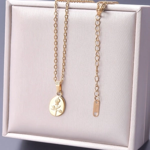 Macro shot of 18k gold plated stainless steel flower pendant on a beige leather jewelry box