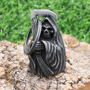 Detailed view of vintage silver Grim Reaper pendant placed on natural tree bark texture