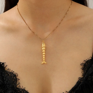 Detail of a dainty gold fishbone pendant necklace on a minimalist O-chain necklace