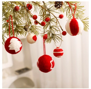 Detail of wool felt Christmas balls with heart and tree patterns on festive branches