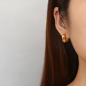 Detail view of gold chunky U-shaped geometric earrings on model with metallic luster