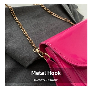 Close-up of the golden rotating metal hook and stitching on the bright rose pink handbag