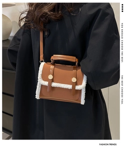 Detail of a brown leather shoulder bag with white fleece trim and gold buckle accents
