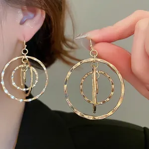 Gold layered concentric circle drop earrings with hammered metal texture and geometric style