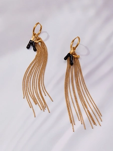 Detail of gold huggie earrings with black round bead chain tassels and drip oil charms