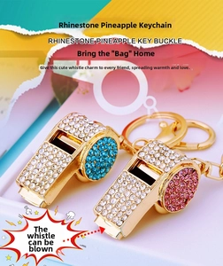 Macro detail of rhinestone-encrusted metal whistle keychains with blue and pink crystal accents
