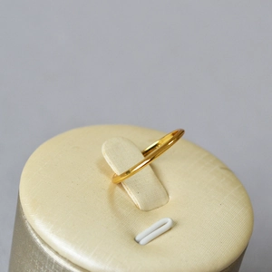 Macro shot of a minimalist gold-plated wavy curve thin stacking ring on a soft background