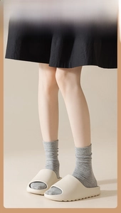 Close-up of cream platform slides worn with grey knitted mid-calf socks for women