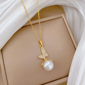Close-up of golden butterfly necklace with sparkling crystals and a white pearl detail