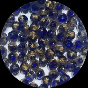 Macro shot of dark blue glass beads with gold foil leaf inside for DIY jewelry
