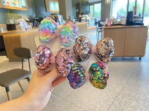 Close-up of sparkling sequin bow hair clips in vibrant rainbow and pastel colors