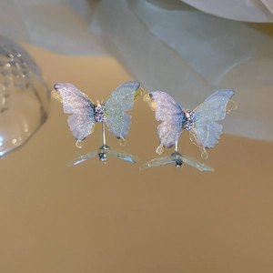 Vue macro des boucles d'oreilles papillon avec paillettes bleu-violet et strass centraux