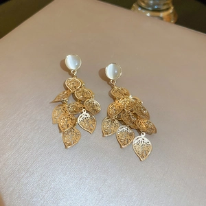 Macro shot of gold tassel earrings with opal stones and hollow leaf pendants